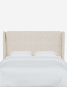 an upholstered bed with white sheets and pillows