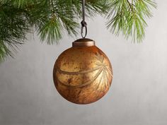 an ornament hanging from a pine tree with the shape of a leaf on it