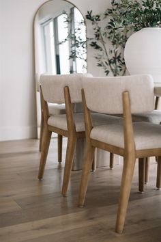 a dining room table with four chairs and a large mirror in the back wall behind it