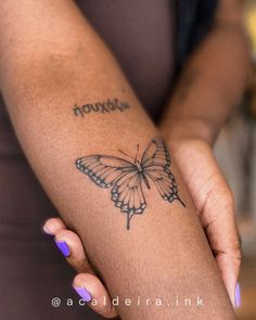 a woman's arm with a butterfly tattoo on it and the words, nouri written in cursive writing