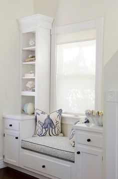 an image of a window seat with pillows on it in front of a white cabinet