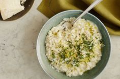 a bowl filled with rice and parsley on top of a table next to a spoon