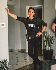 a police officer standing in front of a door pointing to the side with his hand up