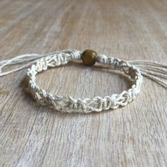 a close up of a rope bracelet on a table with a wooden bead in the middle