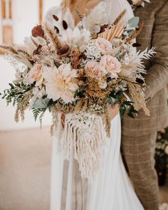 the bride and groom are holding their bouquets in front of each other with feathers on them