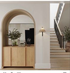 an arched doorway leading to a living room with stairs and plants on the sideboard