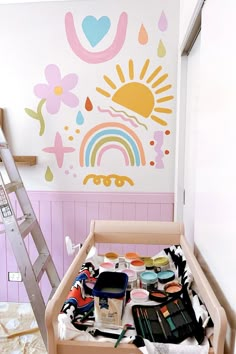 a child's room with a ladder and painted wall behind the crib is full of art supplies