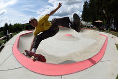 a man riding a skateboard up the side of a cement ramp in a park