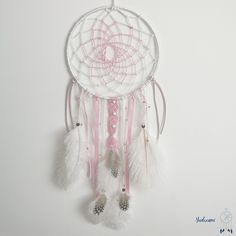 a pink and white dream catcher hanging on the wall