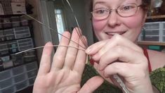 a woman is smiling as she holds up some wire with her hands and looks at the camera