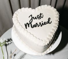 a heart shaped cake with the words just married written on it next to some flowers