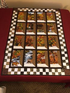 a bed with a red blanket on top of it and a black and white checkered quilt