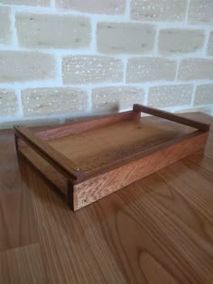 a wooden tray sitting on top of a hard wood floor next to a brick wall