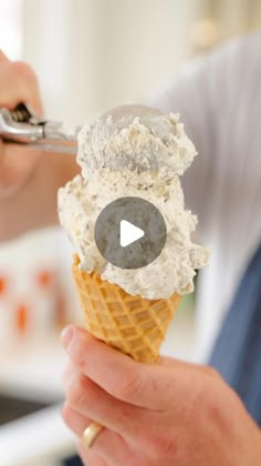 a person holding an ice cream cone with a spoon in their hand and scooping it