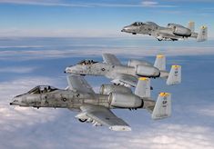 four fighter jets flying in formation above the clouds