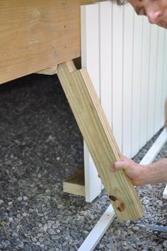 a man working on a wooden bench with wood slats around it's sides