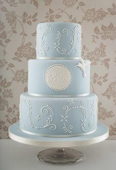 a three tiered blue wedding cake sitting on top of a table