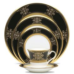 black and gold dinnerware set with matching saucer, cup and saucer in the middle