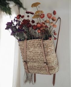 a straw bag with flowers in it hanging on the wall