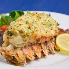 a white plate topped with crab cakes next to a salad and lemon wedge on top of it