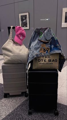 two pieces of luggage sitting next to each other in an airport lobby with clothes on them