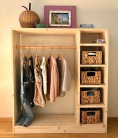 a wooden shelf with baskets and clothes hanging on it