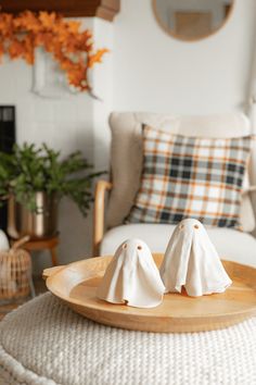 two small white birds sitting on top of a wooden tray in front of a couch