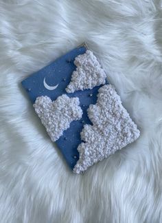 a crocheted pillow with the moon and stars on it sitting on a fluffy white surface