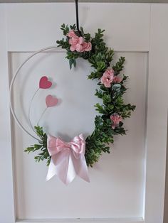 a wreath with pink flowers and hearts hanging on the wall