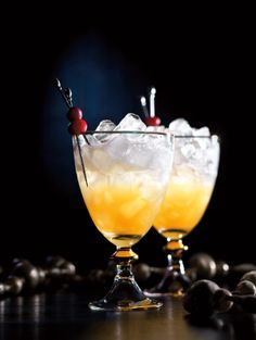 two glasses filled with drinks sitting on top of a table