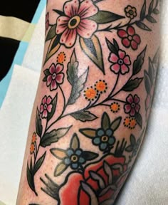 a close up of a person's arm with flowers and leaves tattooed on it