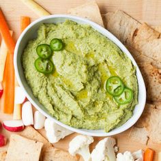 a bowl of guacamole surrounded by sliced carrots and celery