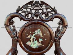 an ornate wooden chair with carvings on the back and sides, decorated with flowers and birds