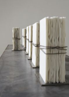 several stacks of white books tied together with twine on top of each other in front of a wall