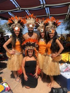 a group of people standing next to each other wearing costumes and headdresses