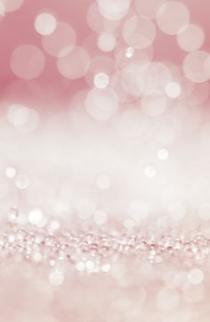 a pink and white background with some glitter on the bottom right hand corner, as well as blurry lights in the middle