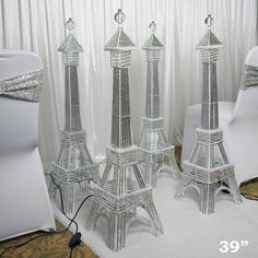 the eiffel tower is made out of plastic and sits in front of two white chairs