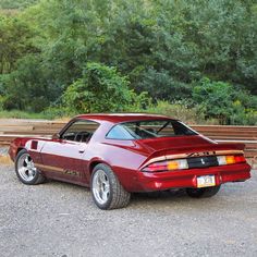 a red sports car parked on the side of a road next to some wooden benches