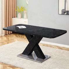 a black marble dining table with an x design on the top and metal base, in a living room