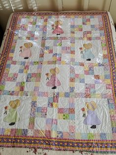 a child's bed with a quilt on it that has little princesses all over it