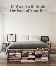 a bed with lots of books on it in a room that has hardwood floors and white walls