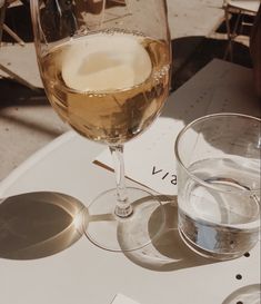 a glass of wine sitting on top of a table next to two glasses of water