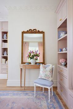 a chair sitting in front of a mirror on top of a wooden table next to a shelf