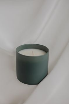 a green candle sitting on top of a white sheet