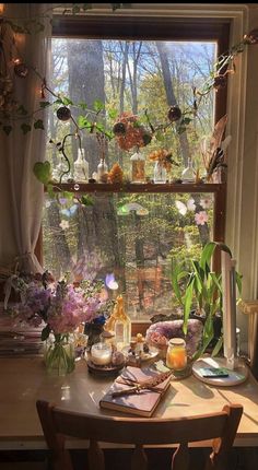 a wooden table topped with lots of vases filled with flowers next to a window