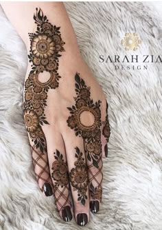 a woman's hand with henna on top of her fingers and hands are decorated with flowers