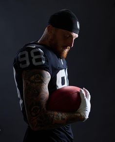 a tattooed man holding a football in his hands