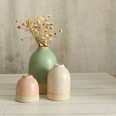 two vases with flowers in them sitting on a white table top next to each other