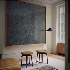 a living room with two stools and a large painting on the wall behind it