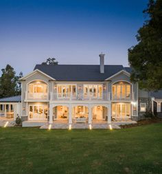 a large white house with lots of windows and lights on it's front lawn